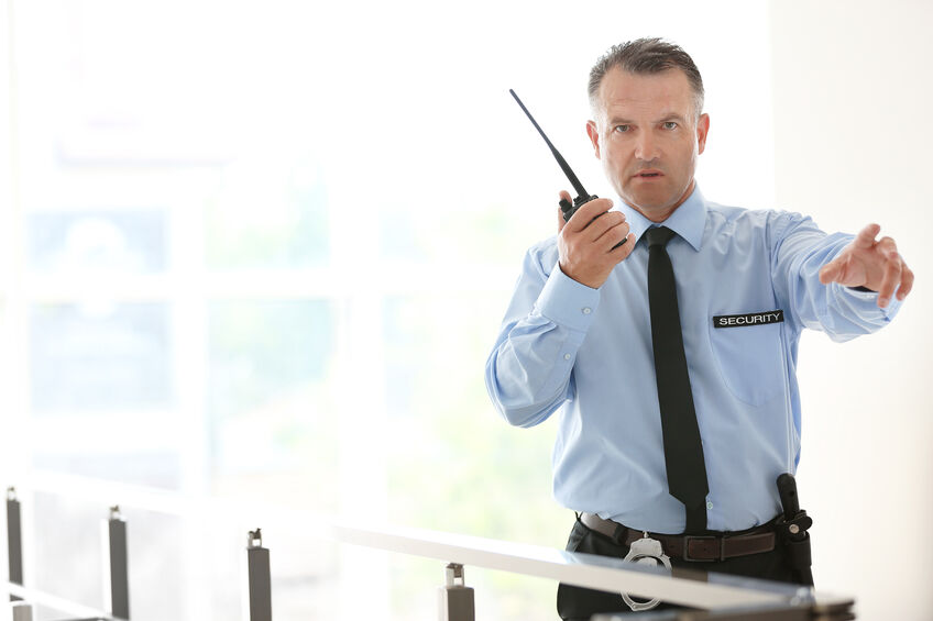 Male security guard using portable radio on a commercial setting 